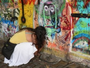 Girl writing graffiti on the Lennon wall in Prague