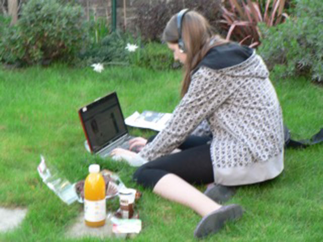 Young woman sitting on grass looking at a laptop